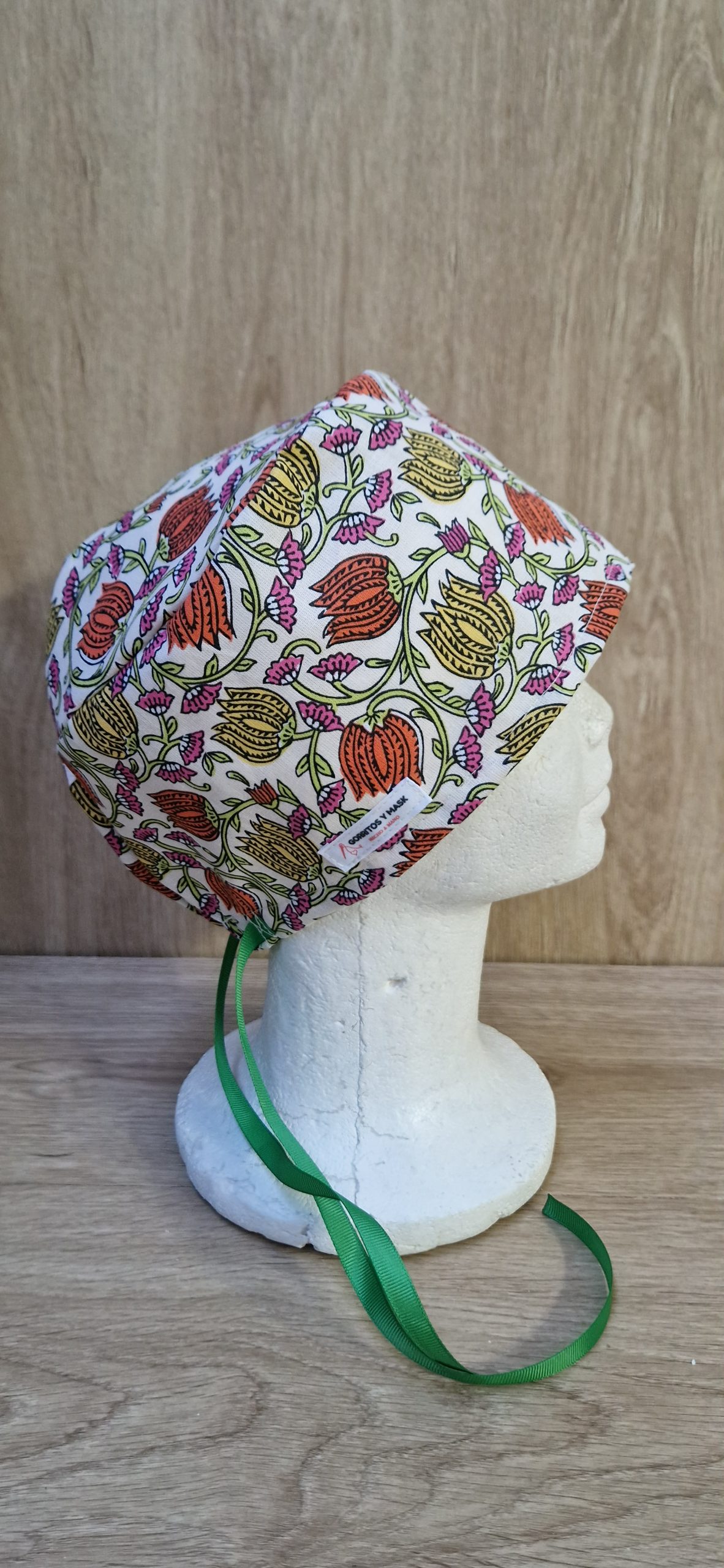 Gorro sanitario modelo Divali Flor fabricado en algodón 100% cretona con estampado floral. Disponible en versión para pelo corto o pelo largo, incorpora sistemas de ajuste cómodos y seguros para profesionales sanitarios.